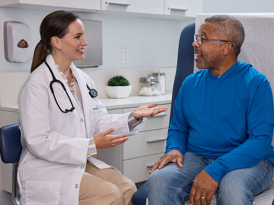 Male patient talking with female doctor at the doctors office.​​ 